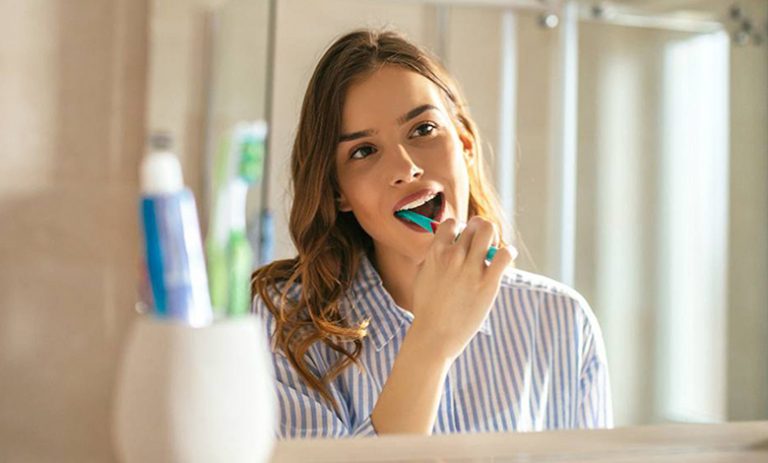 Девушка чистит зубы дома